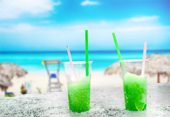 Two apple green drift-ice with straw on the beach. In the background is blue sky, palms, sea nd sandy beach. This is situated in tropical resort in Asia © Jana