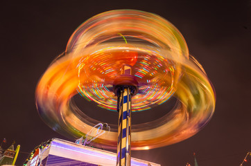 A spinning roundabout, photographed with a long exposure. Dynamic bright photo taken in the evening.
