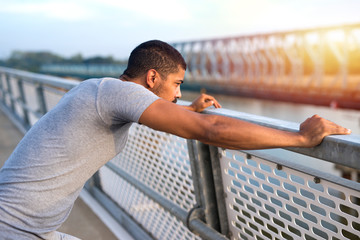 Young sporty man concentrated for training. Focused athlete looking the river in sunset. Sportsman preparing for running. Fitness and healthy lifestyle.