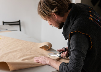 Obraz premium Young man tailor with scissors making clothing pattern