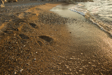 human foot print on wet sand sea shoreline near water waves in evening twilight sunset time, freedom or summer vacation concept photography