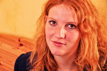 Schönes Portrait in Nahaufnahme einer offen lächelnden jungen rothaarigen lockigen Frau im...