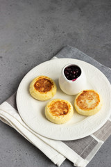 Cottage cheese pancakes or fritters with blueberry sauce and mint. Traditional Ukrainian and Russian cuisine. Syrniki. Healthy and diet breakfast.