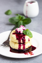 Cottage cheese pancakes or fritters with blueberry sauce and mint. Traditional Ukrainian and Russian cuisine. Syrniki. Healthy and diet breakfast.