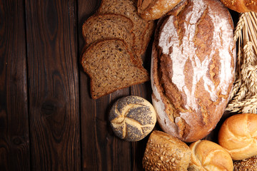Different kinds of bread and bread rolls on board from above.