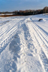 Fototapeta na wymiar Closeup Details of Tire Marks in Snow on Sunny Winter Day