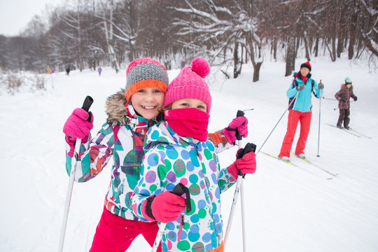 little girls cross-country skiing in the winter forest in the snow