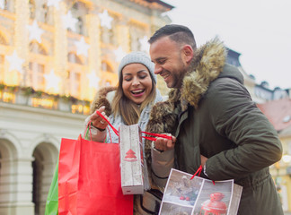 Man and woman show each other gifts they bought in Christmas shopping for their loved ones. consumerism concept