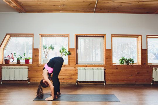 Caucasian woman is practicing yoga at studio padahastasana .