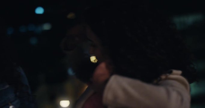 beautiful woman friends making faces on rooftop at night having fun posing with silly expressions enjoying urban nightlife together bokeh city lights in background