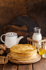 Homemade thin crepes with honey, pancakes on wooden rustic background