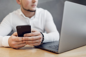Portrait of Young man with a mobile phone sitting at cafe using laptop.