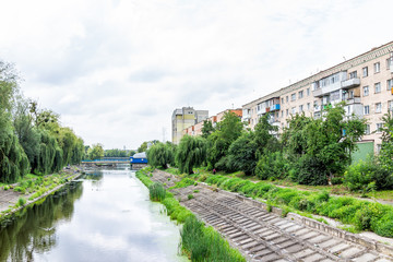 Fototapeta na wymiar Green park in Myru or peace avenue in Naberezhna St, street, Rivne, western Ukraine and Ustya river in summer, reflection of sky