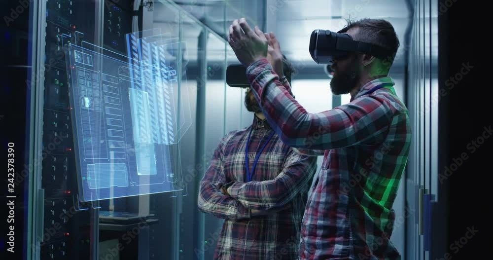 Wall mural medium shot of two male technician in vr glasses using a virtual interface while working in a data c