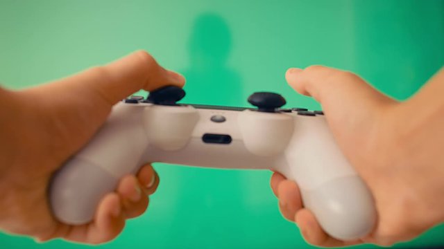 Gamepad in the player's hands opposite the large flat screen with green screen, 4k