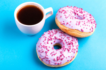 Two tasty lilac donuts with sprinkle, cup of strong coffee
