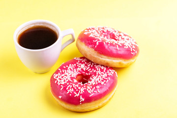 Two delicious pink donuts with sprinkle and cup of coffee