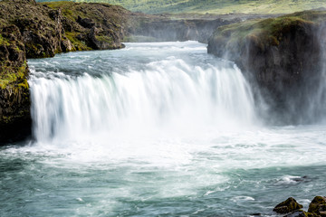 Obraz premium Godafoss, Iceland waterfall of the gods with long exposure smooth motion of water falling off cliff in green moss summer landscape