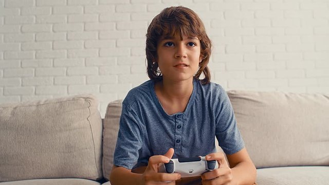 Young pre teenage boy is playing video game console, have fun, laugh, hold the joystick, 4k