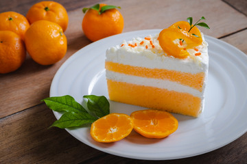 Orange cake and fresh orange on white plate