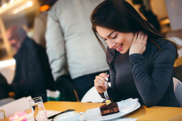 Woman eating a piece of cake at cafe