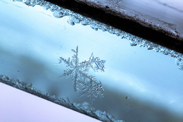 Beautiful snow flake on a light blue background close up
