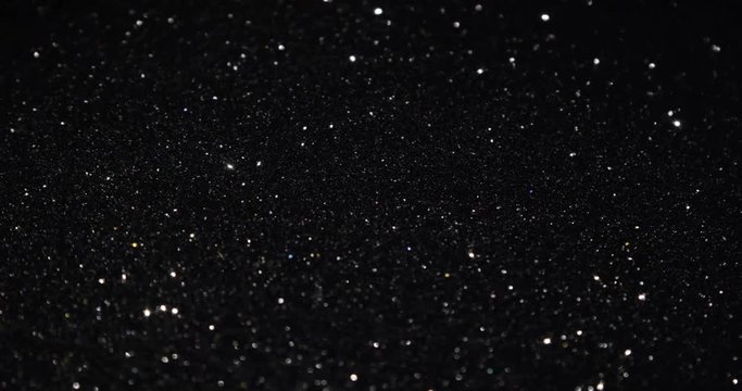 Black glitter texture surface rotating. Close up 4k backdrop footage.