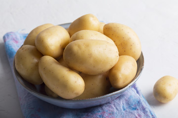 Pile of raw potatoes in the bowl on white background