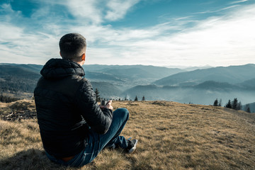 Naklejka na ściany i meble a man with a metal cup sits on a background of mountains