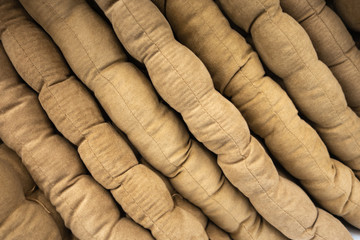 Gray and beige pillows are folded on the shelf in the store. Creative vintage background.