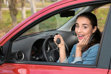 Happy woman showing key from new car