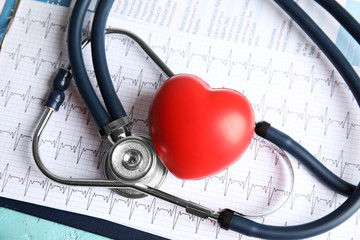 Stethoscope, red heart and cardiogram on table. Cardiology concept