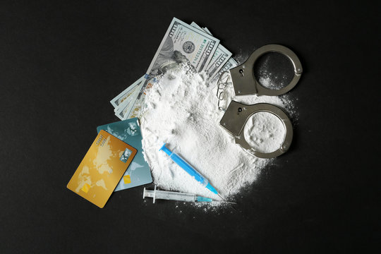 Composition with heap of cocaine and syringes on black background, top view