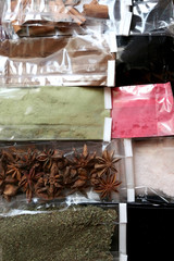 Small plastic bags full of various spices and herbs: anise, cinnamon, himalayan salt, leek, raspberry, shallots and others. Top view.