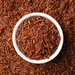 Ceramic bowl with raw brown rice on cereal, top view