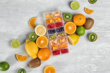 Flat lay composition with ice cube tray and fresh fruits on light background