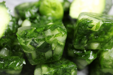 Ice cubes with cucumber slices and herbs, closeup
