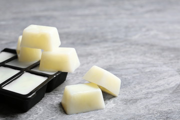 Ice cubes made with milk and tray on grey table. Space for text