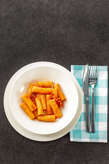Penne Amatriciana fresh pasta with parmesan cheese on dark background