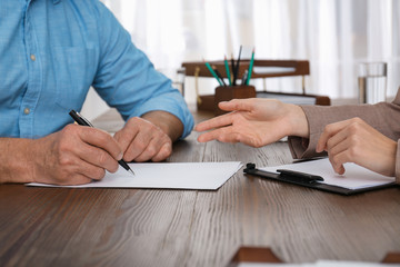 Senior man signing document in lawyer's office