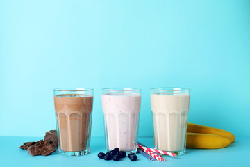 Glasses with different protein shakes and ingredients on color background. Space for text