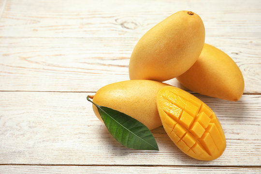 Composition with fresh mango fruits on wooden background. Space for text