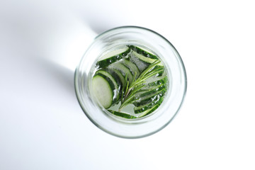 Glass of fresh cucumber water on white background, top view
