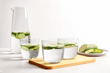 Glasses and jug of fresh cucumber water on table