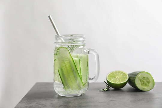Mason jar with fresh cucumber water on grey table