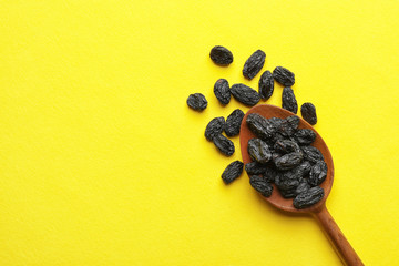 Spoon with raisins and space for text on color background, top view. Dried fruit as healthy snack