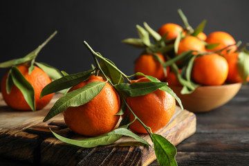 Wooden board with ripe tangerines on table