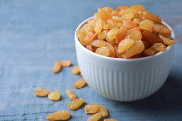 Bowl with raisins on wooden table, space for text. Dried fruit as healthy snack