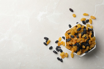 Bowl of raisins on grey background, top view with space for text. Dried fruit as healthy snack