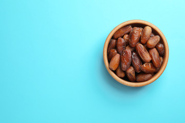 Bowl with sweet dried date fruits on color background, top view. Space for text